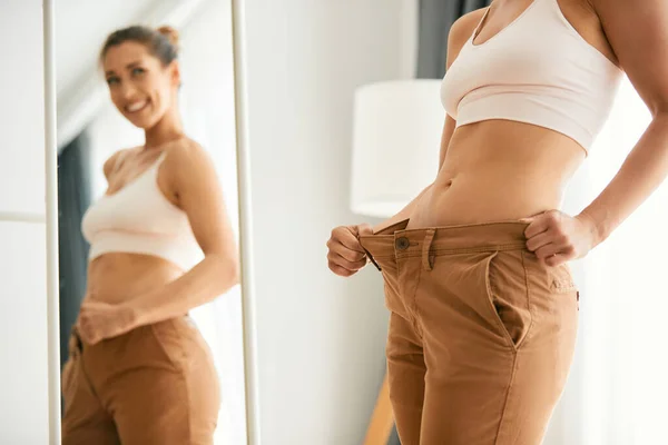 Woman showing weight loss results in loose pants